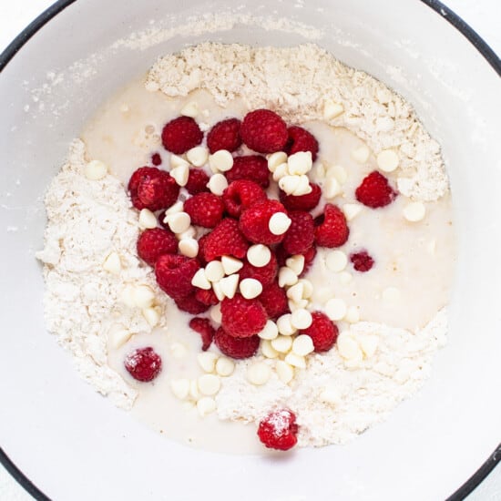 A bowl with raspberries and white chocolate in it.