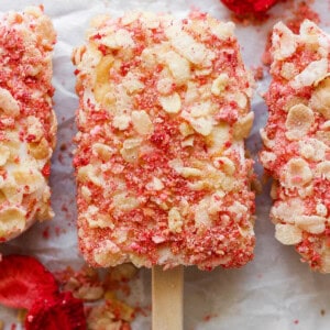 Three popsicles with strawberries and almonds on them.