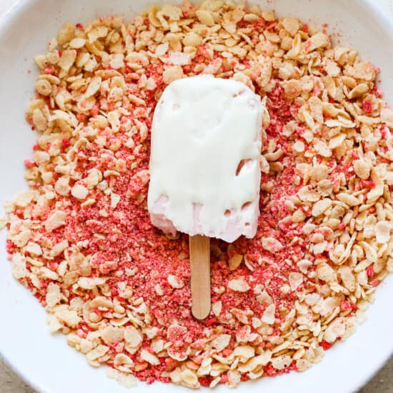 A bowl of granola with a popsicle on top.