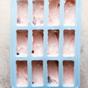 A blue ice cube tray filled with pink ice cream.
