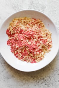 Pink granola in a white bowl.