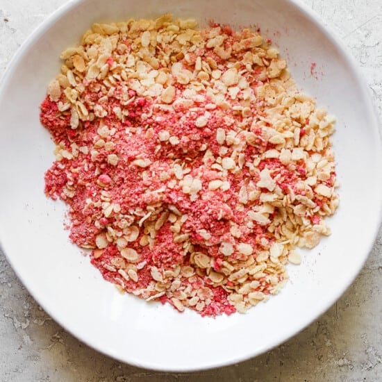 Pink granola in a white bowl.