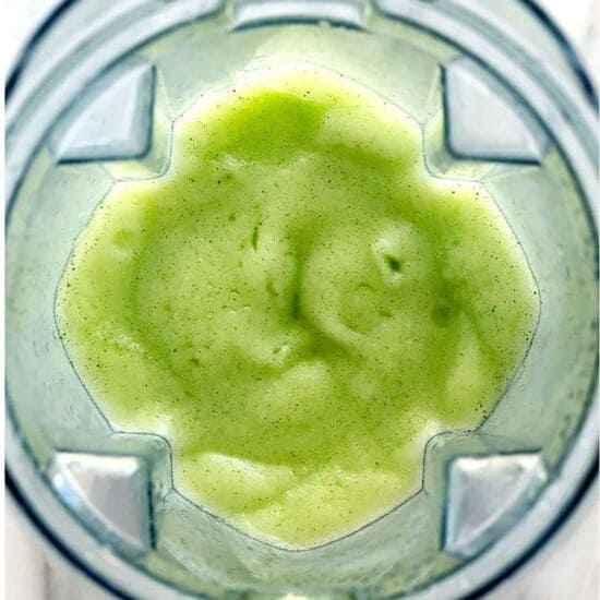 A close up of a vi،nt green smoothie resembling mojitos, blended to perfection.
