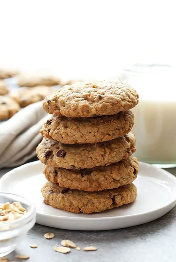 Healthy stack of oatmeal cookies on a plate next to a glass of milk.