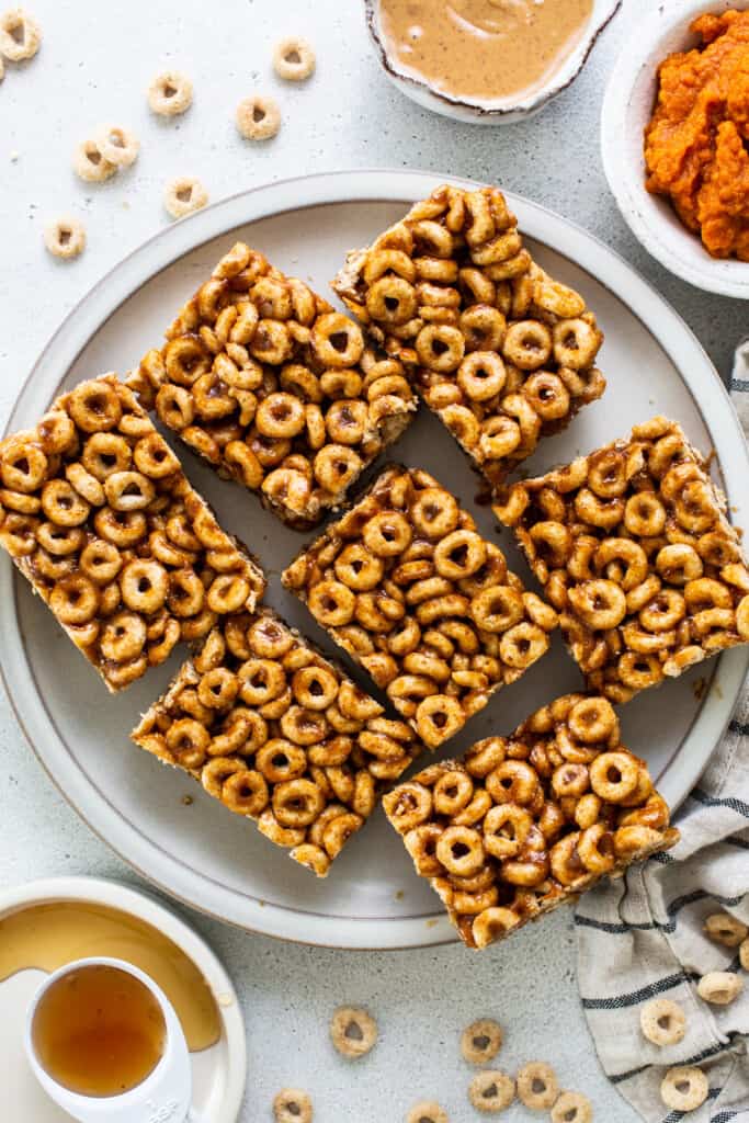 A plate with a plate of cereal bars and a bowl of peanut butter.