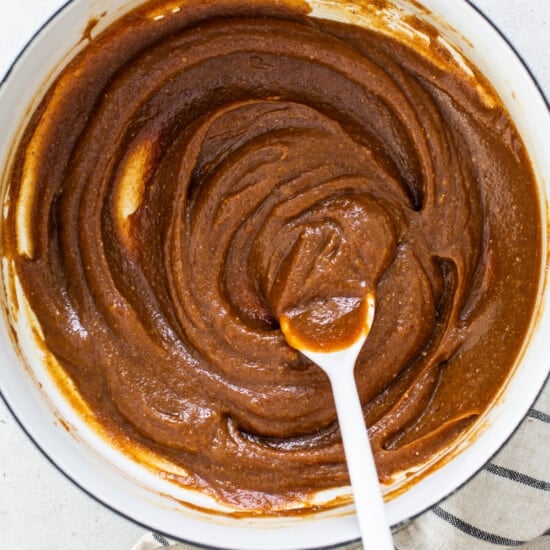 A bowl of peanut butter in a pan with a spoon.