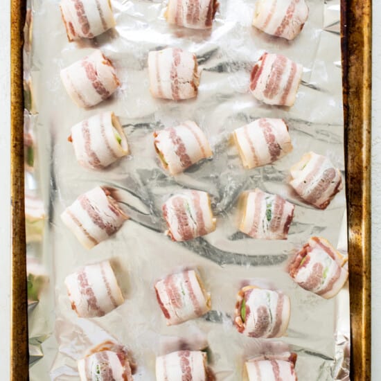 Bacon wrapped in foil on a baking sheet.