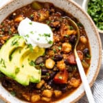 A bowl of black bean chili with avocado and sour cream.
