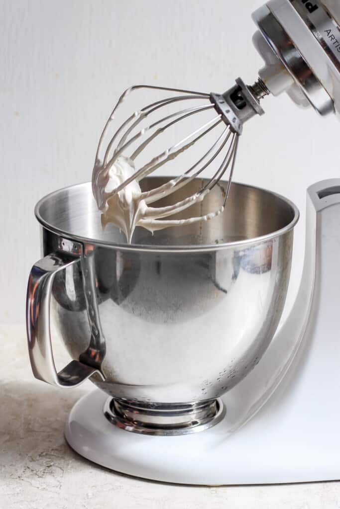 A white mixer with a whisk in it.