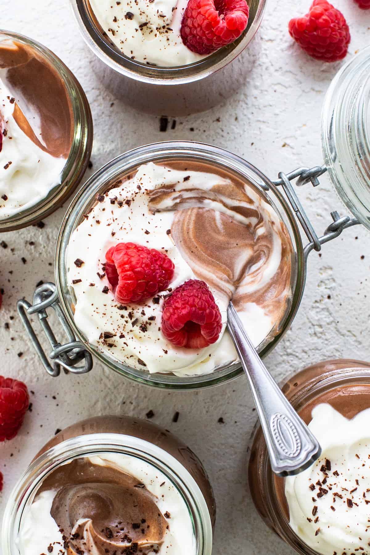 Chocolate mousse in jars with raspberries and whipped cream.