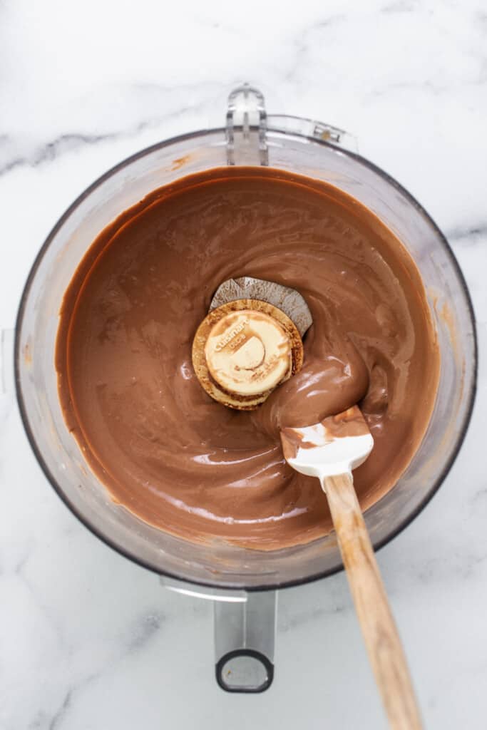 Chocolate ganache in a mixing bowl with a wooden spoon.