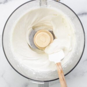 Whipped cream in a mixing bowl with a wooden spoon.