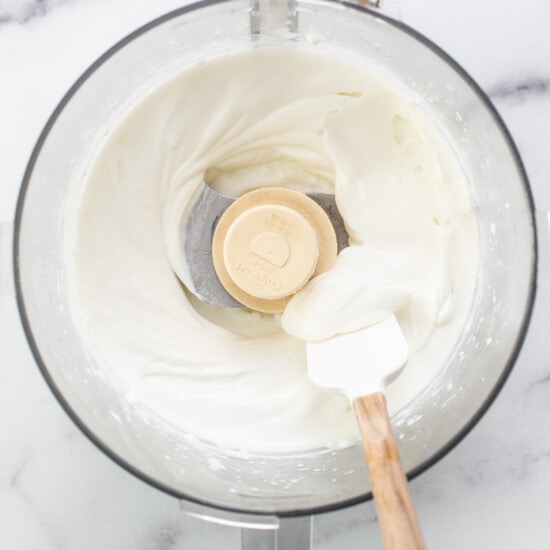 Whipped cream in a mixing bowl with a wooden spoon.
