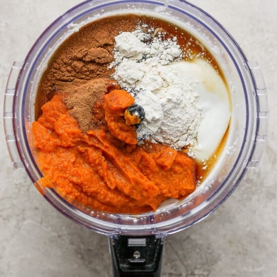 A food processor filled with ingredients for a pumpkin pie.