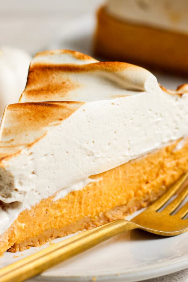 A slice of pumpkin pie on a plate with a fork.