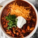 Instant pot chili with sour cream and cheese served in a white bowl.