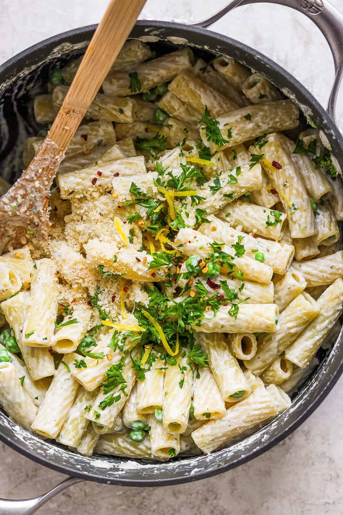 Penne pasta in a pan with parmesan cheese and parsley.