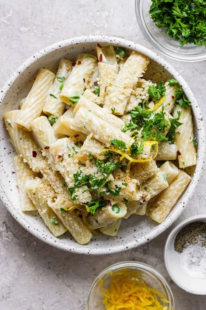 Penne pasta with lemon and herbs in a white bowl.
