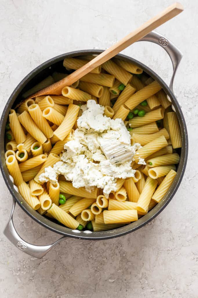 Penne pasta with peas and feta cheese in a skillet.