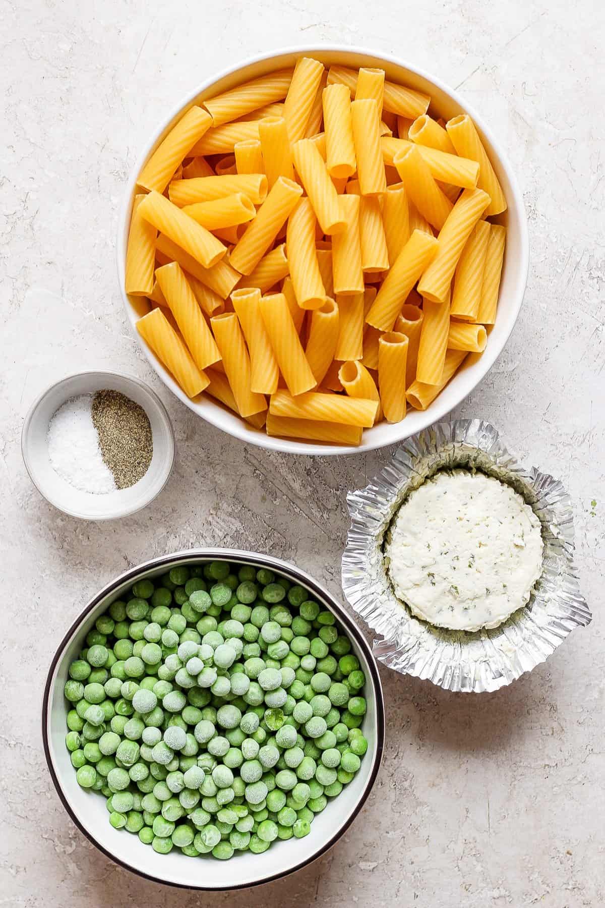 A bowl of pasta, peas and other ingredients.