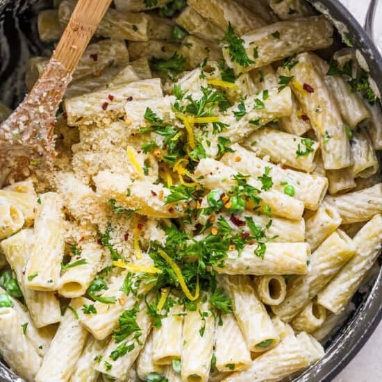 Penne pasta in a pan with parmesan cheese and parsley.