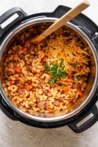 An instant pot full of macaroni and cheese with a wooden spoon.