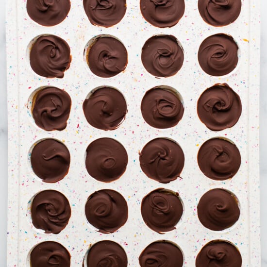 A tray of chocolate dipped cupcakes on a marble countertop.