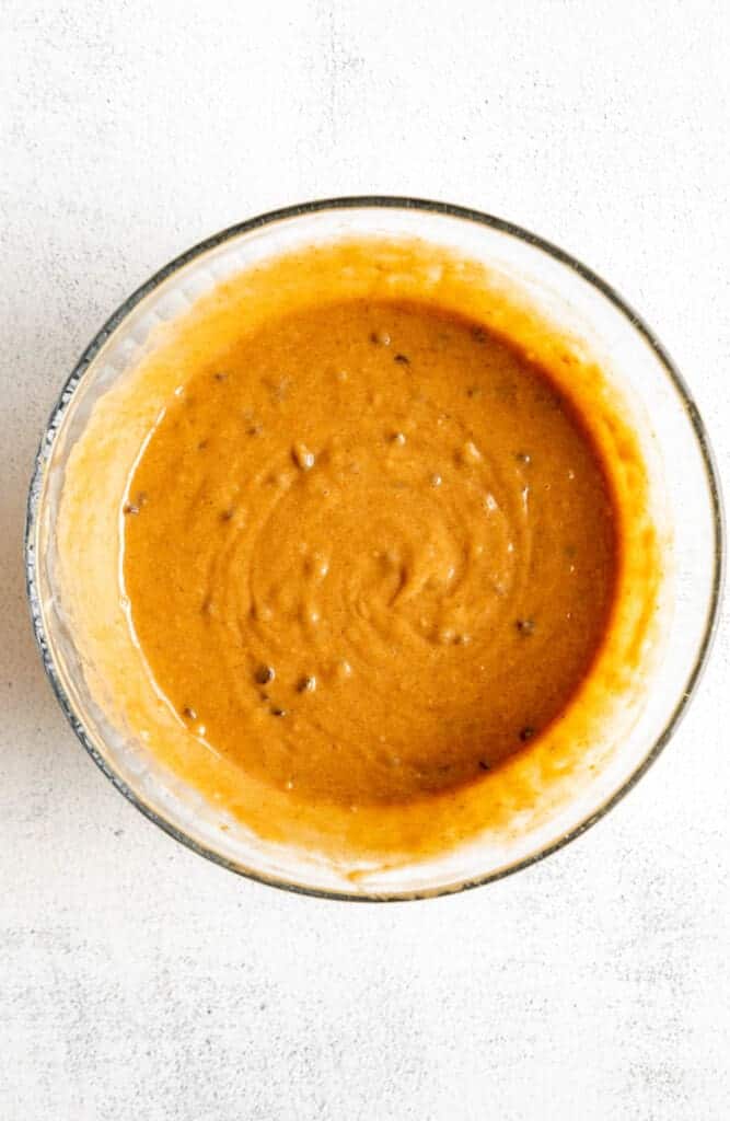 A bowl with a sauce on a white surface.