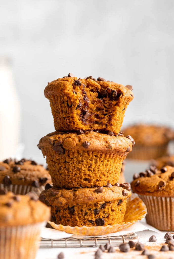 A stack of pumpkin chocolate chip muffins with a bite taken out.
