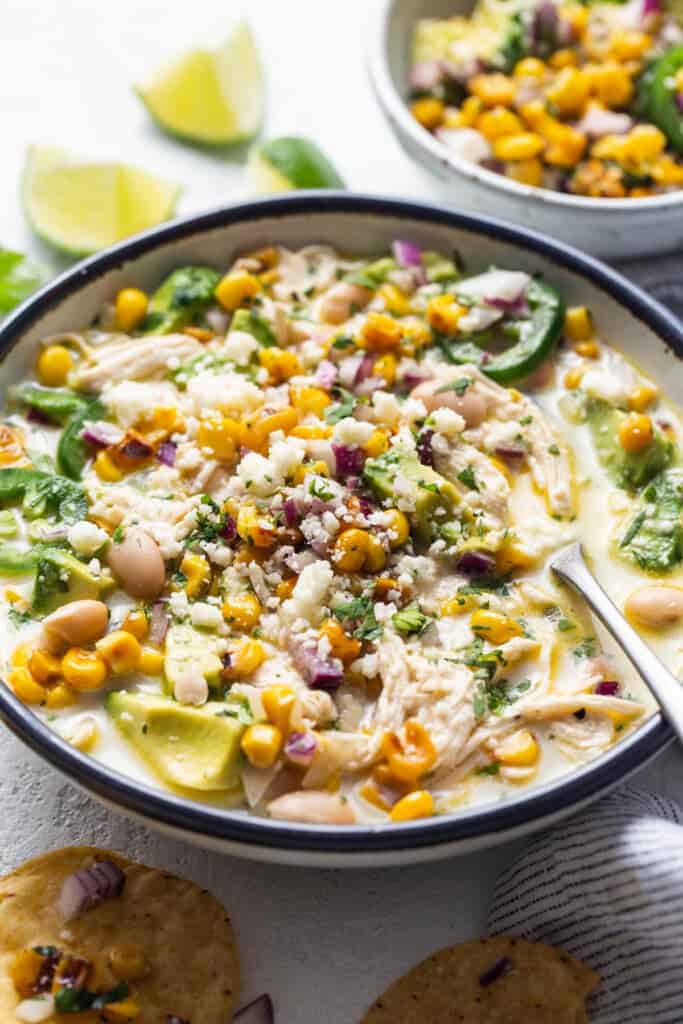 A bowl of chicken and corn soup with tortilla chips.