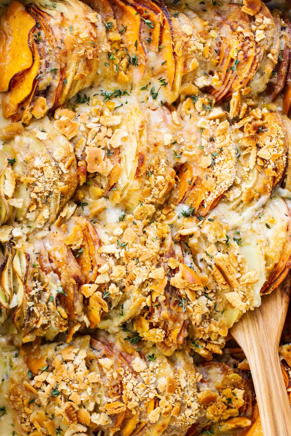 A dish of roasted sweet potatoes with a wooden spoon.