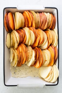 Sliced sweet potatoes in a baking dish.