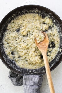 A frying pan with a wooden spoon in it.