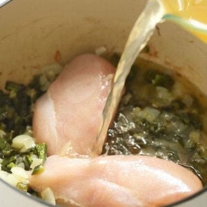 Chicken breasts being poured into a pan with green chili.