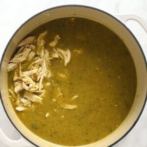 A pot of green chili soup with chicken.