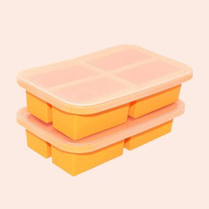 A stack of orange ice cube trays on a beige background.