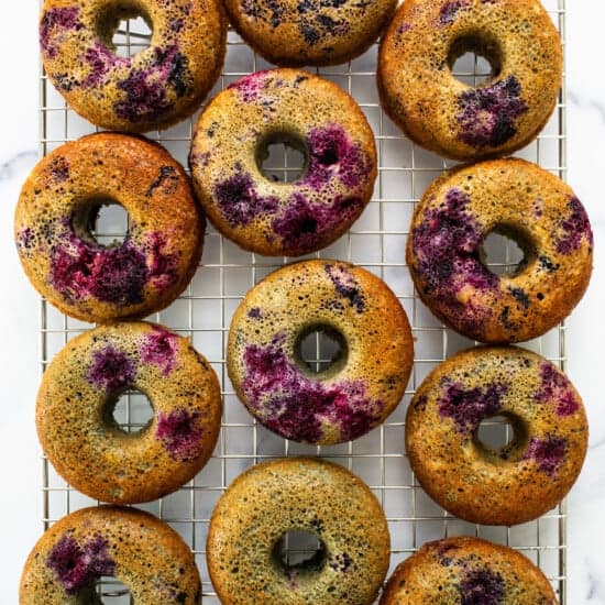 Blueberry donuts on a cooling rack.