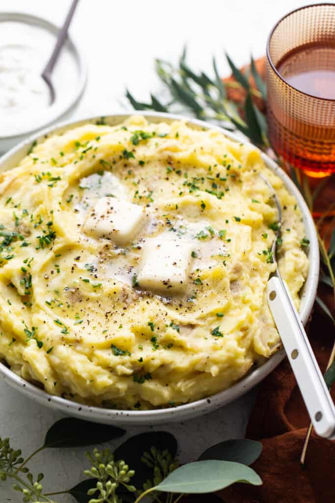 A bowl of mashed potatoes with sour cream and herbs.