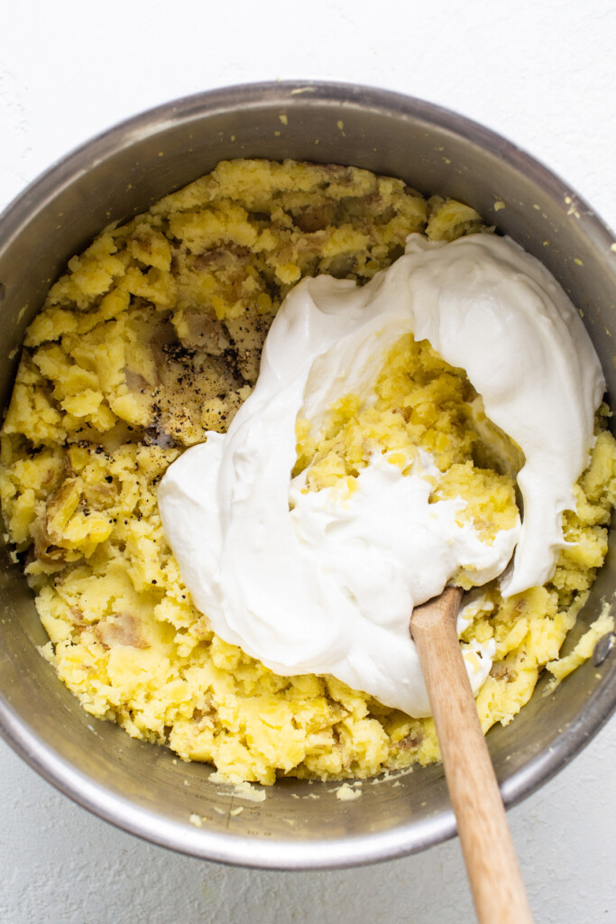 A bowl of batter with whipped cream and a wooden s،.