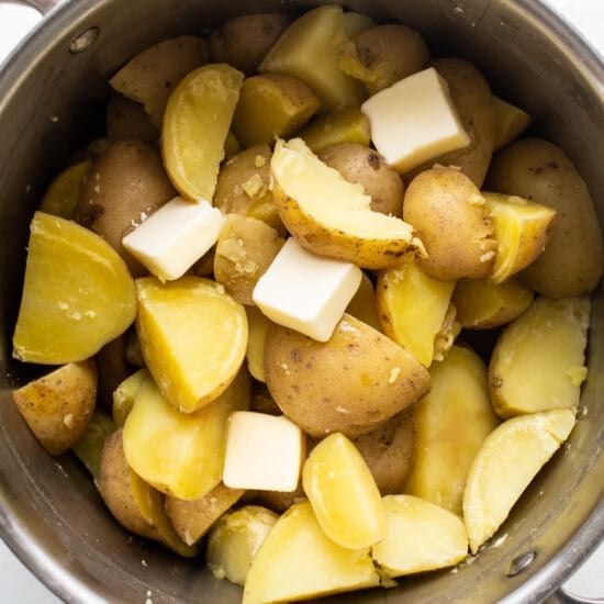 Potatoes and cheese in a pot on a white background.