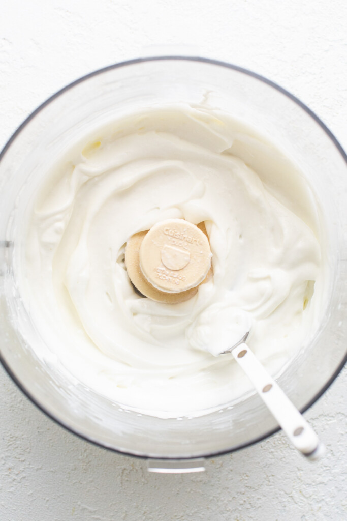 A bowl of whipped cream with a banana slice in it.