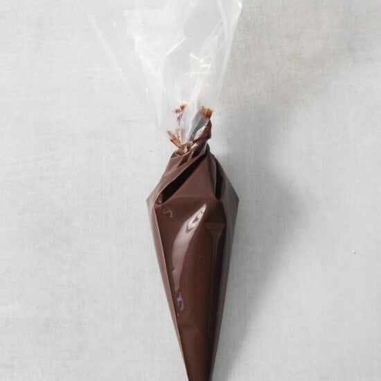 A chocolate cone wrapped in plastic on a concrete surface.
