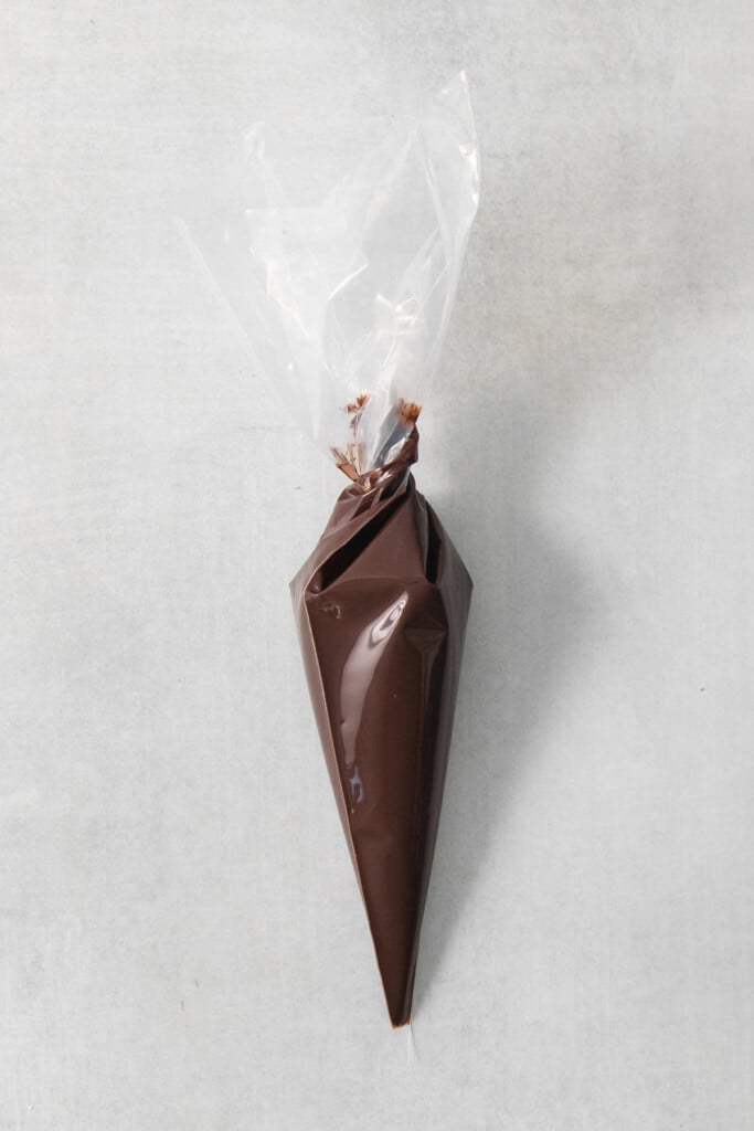 A cone of chocolate wrapped in plastic on a concrete surface.