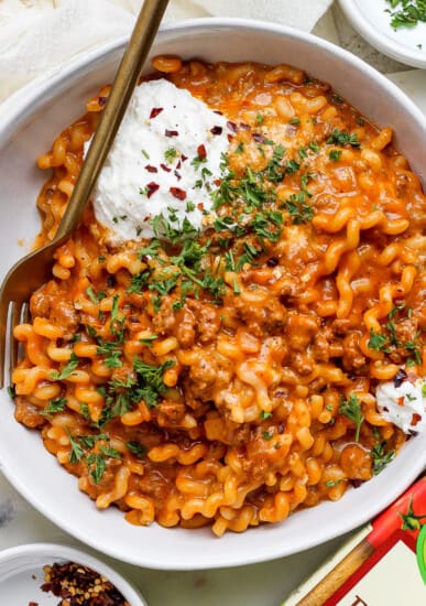 A bowl of pasta with meat sauce and sour cream.