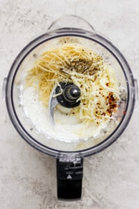 A food processor filled with ingredients for a pasta dish.