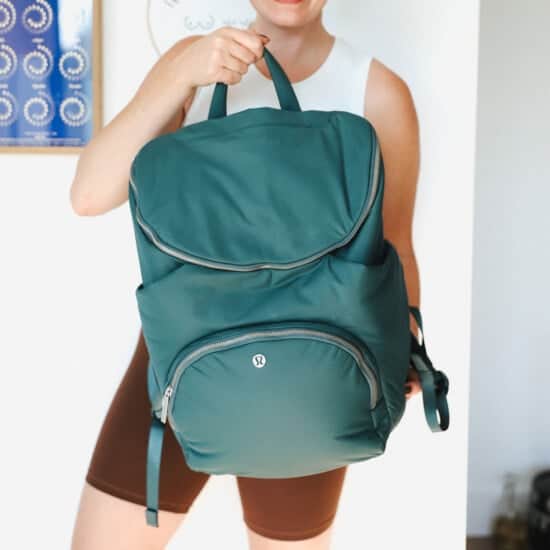 A woman holding a green backpack.