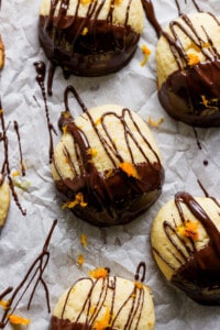 A group of cookies with chocolate and orange drizzle on them.