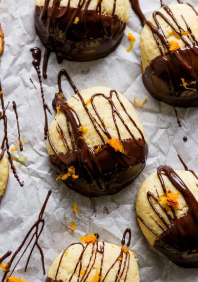 A group of cookies with chocolate and orange drizzle on them.