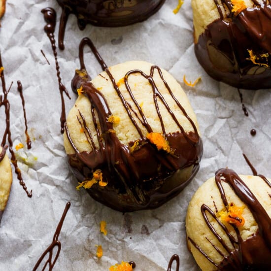 A group of cookies with chocolate and orange drizzle on them.