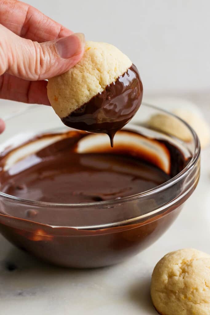 A person dipping a cookie into a bowl of chocolate.